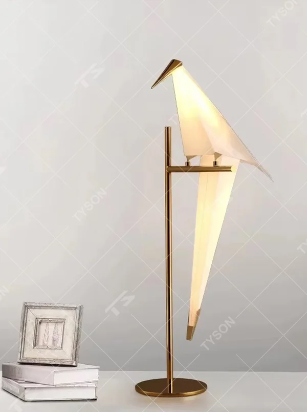 This artistic origami crane-shaped table lamp features a gold metal stand and base, paired with a translucent material to create an origami crane lampshade. It serves both lighting and decorative purposes, ideal for light luxury art-style spaces such as bedroom bedside tables, living room side tables, and hotel guest rooms.