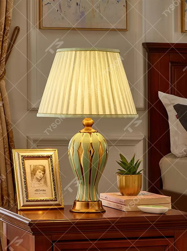 European-style light luxury ceramic table lamp, with a green-gold gradient wavy ceramic base, off-white pleated fabric lampshade and gold metal details, providing soft and warm light, designed to enhance the retro and elegant atmosphere of spaces, suitable for bedroom nightstands, living room side tables, European-style homes and hotel guest rooms, etc.
