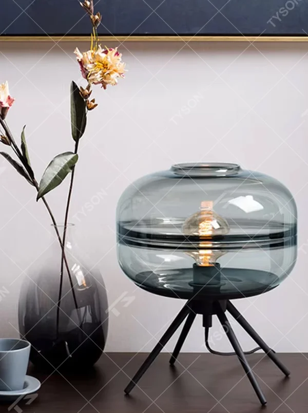 This set of Nordic-style glass lighting includes a table lamp and a chandelier, with drum-shaped lampshades made of blue-gray gradient glass. The table lamp is paired with a black tripod base, and the chandelier uses a suspension design, emitting soft and transparent light, serving both lighting and decorative purposes, ideal for bedrooms, dining rooms, Nordic-style homes and internet-famous shops and other scenarios.