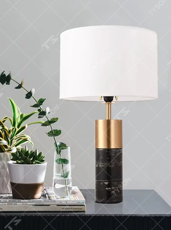 This light luxury table lamp features a black marble (with white veins) base, paired with a gold metal cylindrical lamp body and an off-white fabric cylindrical lampshade, with a gold spherical decoration on top. It serves both lighting and decorative purposes, ideal for light luxury spaces such as bedroom bedside tables, living room side tables, and hotel guest rooms.