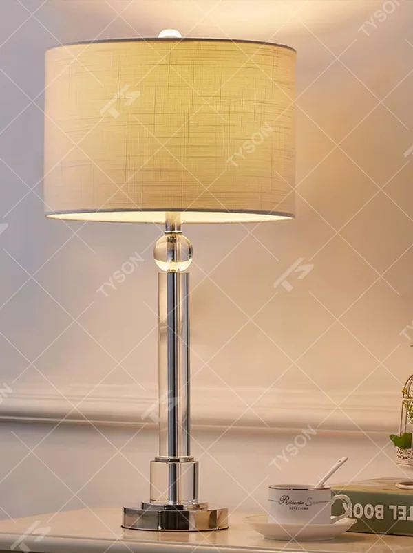 Light luxury crystal column table lamp, transparent cut crystal column base with silver metal details and white fabric lampshade, available in a set of two sizes, soft and even light, designed to enhance the delicate and elegant atmosphere of spaces, suitable for bedroom nightstands, living room side tables, modern light luxury homes and hotel guest rooms, etc.