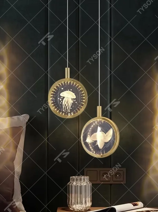 This light luxury small round chandelier features a gold metal frame, a transparent panel with delicate patterns such as jellyfish/birds, and projects ripple light and shadow on the wall when lit, serving both lighting and decorative purposes, ideal for bedroom bedside tables, light luxury homestays, high-end hotel rooms and other spaces.