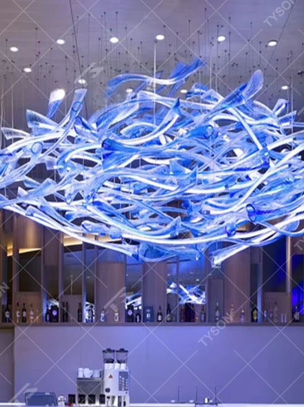 This large custom art glass chandelier features a streamlined nebula/wave shape woven from blue-white gradient transparent glass strips, suspended in a floating manner, serving both lighting and artistic decoration purposes, ideal for high-ceiling commercial spaces such as hotel lobbies, high-end bars, and sales offices, with free design and professional engineering customization available.

