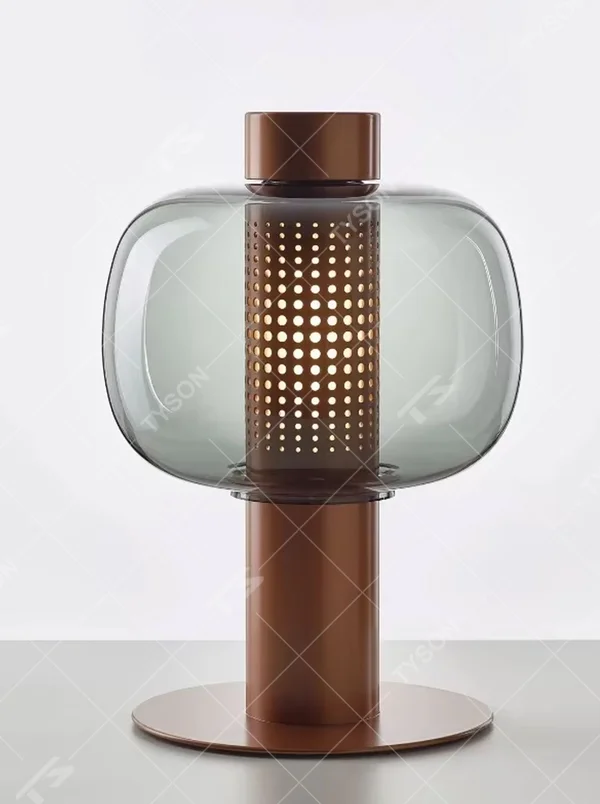 This modern minimalist table lamp features a copper-colored metal frame, paired with an oval smoked glass lampshade and a perforated metal lamp core. Its shape combines roundness with industrial details, and light passes through the perforations and glass to create soft, dappled light and shadow. It serves both lighting and decorative purposes, ideal for bedroom bedside tables, living room side tables, hotel guest rooms, and modern office spaces.