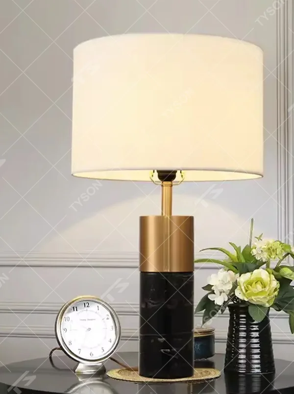 This light luxury modern table lamp features a lamp post made of black marble and gold metal, paired with an off-white fabric cylindrical lampshade. It has a calm and elegant shape, serves both lighting and decorative purposes, and is ideal for bedroom bedside tables, living room side tables, hotel guest rooms and light luxury commercial spaces.