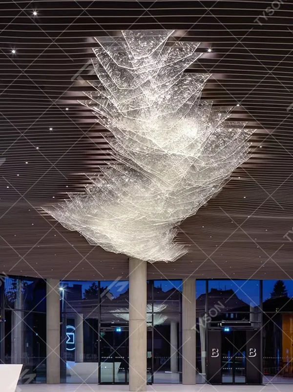 This large suspended art chandelier is woven into a flowing wave shape with slender light-transmitting materials, presenting a translucent light gold color, serving both lighting and art installation functions, ideal for high-ceiling commercial spaces such as hotel lobbies, corporate exhibition halls, and high-end clubs.
