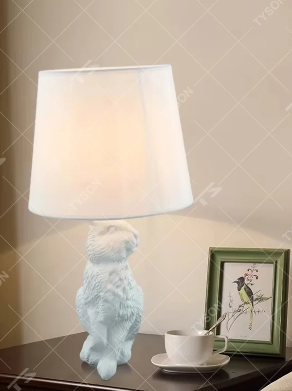 This dark art style table lamp features a bionic rabbit-shaped base made of black resin, paired with a black fabric cylindrical lampshade. The rabbit-lifting-lampshade design is full of fantasy, serving both lighting and decorative purposes, ideal for trendy toy spaces, personalized homes, internet-famous shops and other scenarios.
