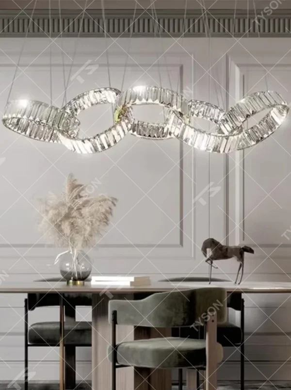 This is a modern light luxury style interlocking crystal chandelier, composed of transparent cut crystal strips forming a chain-like structure, paired with a gold metal suspension base. Light refracts through the crystals to create brilliant and dynamic lighting effects, serving both lighting and artistic decoration purposes, suitable for quality-focused scenarios such as large flat-floor dining rooms, villa living rooms, high-end clubs, and showrooms.