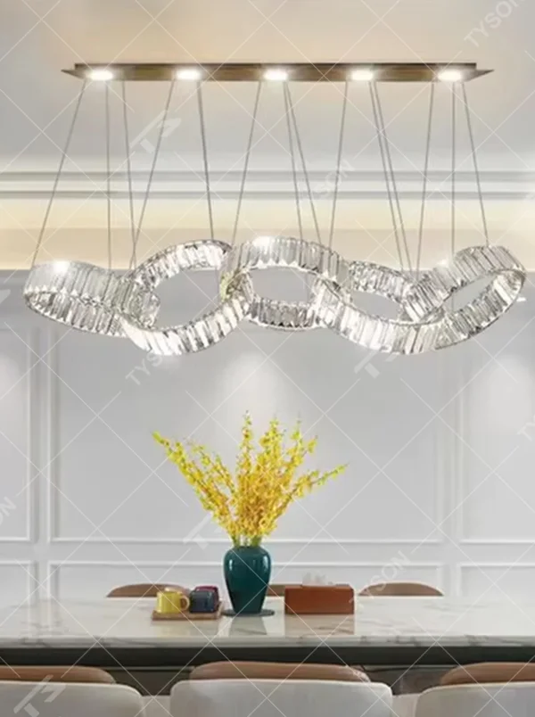 Modern light luxury chain-style crystal chandelier, with a gold long-strip top plate hanging multiple groups of cut-texture crystal links in an interlocking shape, emitting brilliant and transparent light, combining artistic decorativeness and lighting function, suitable for core lighting and atmosphere creation in spaces such as dining rooms, high-ceiling living rooms, and high-end clubs.
