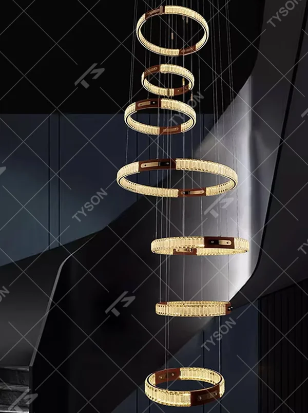 This is a light luxury style multi-layer staggered ring crystal chandelier, featuring a gold metal frame paired with transparent crystal strips. The layered ring shape resembles flowing light rhythm, emitting brilliant and luxurious light, serving both lighting and artistic decoration purposes, suitable for high-ceiling spaces such as villa high-ceiling living rooms, spiral staircases, hotel lobbies, and duplex voids.