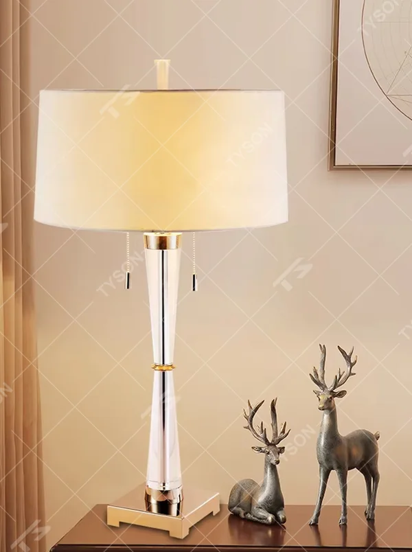 Modern light luxury fabric table lamp, with an off-white fabric lampshade paired with a transparent acrylic + gold metal spliced conical lamp pole, a gold square base with a double pull-cord switch, emitting soft and warm light, combining decorativeness and practicality, suitable for lighting and decoration in spaces such as bedroom nightstands, living room side tables, and hotel guest rooms.