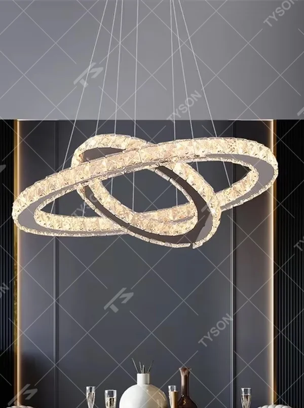 This is a modern light luxury style three-layer ring crystal chandelier, with a silver metal ceiling plate paired with glittering and transparent crystal rings, which has both lighting and decorative functions, suitable for living rooms, dining rooms, villa high-ceiling spaces, etc.