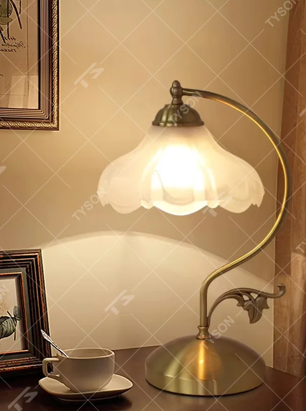 Vintage pastoral style flower-shaped table lamp, with a black wrought iron curved lamp pole with leaf decoration, paired with a white frosted glass petal lampshade. It emits soft and warm light, combining decorativeness and practicality, suitable for lighting and decoration in spaces such as bedroom nightstands, study desks, and B&B guest rooms.