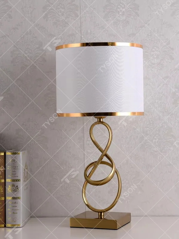 Modern light luxury twisted line metal table lamp, with a gold twisted line lamp pole paired with a beige fabric lampshade (with gold trim on the edge), a square gold base, emitting soft and warm light, combining decorativeness and practicality, suitable for lighting and decoration in spaces such as bedroom nightstands, living room side tables, and studies.