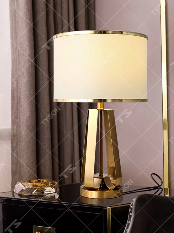 This is a light luxury geometric metal table lamp, featuring a gold polygonal hollow lamp base paired with an off-white fabric lampshade (with gold trim). It emits soft and warm light, serving both lighting and decorative purposes, suitable for bedroom nightstands, light luxury living room side tables, hotel guest rooms, showrooms and other scenarios.