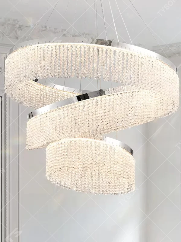 Modern light luxury three-layer spiral ring crystal chandelier, composed of dense crystal particles and silver metal frames in a staggered spiral structure, emitting brilliant and soft light, combining artistic decorativeness and lighting function, suitable for core lighting and atmosphere creation in living rooms, dining rooms, villa high-ceiling spaces, etc.