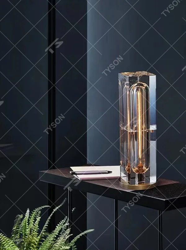 Modern light luxury crystal column table lamp, with a transparent cut crystal outer frame paired with a central gold metal luminous body, and a gold metal base at the bottom, emitting soft and transparent light, combining decorativeness and practicality, suitable for lighting and decoration in spaces such as console tables, living room side tables, study desks, and hotel guest rooms.