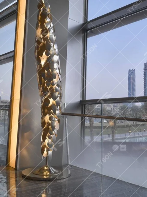 This light luxury art sculpture floor lamp features a twisted scale shape made of metal, with warm light refracting a luxurious halo through the metal texture, serving both lighting and decorative purposes, suitable for luxury spaces such as high-end hotel lobbies and clubs.