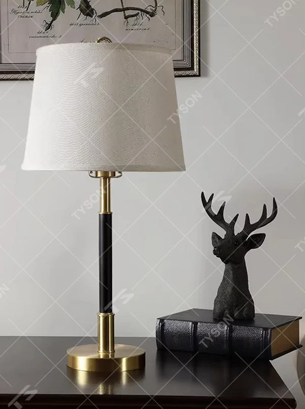 This table lamp features a black and gold contrasting metal lamp pole paired with an off-white fabric lampshade, with a glossy gold metal base. It presents a style that combines modern light luxury and minimalist retro, with soft eye-protective light, serving both lighting and decorative purposes, suitable for placement in bedrooms, studies and other spaces.
