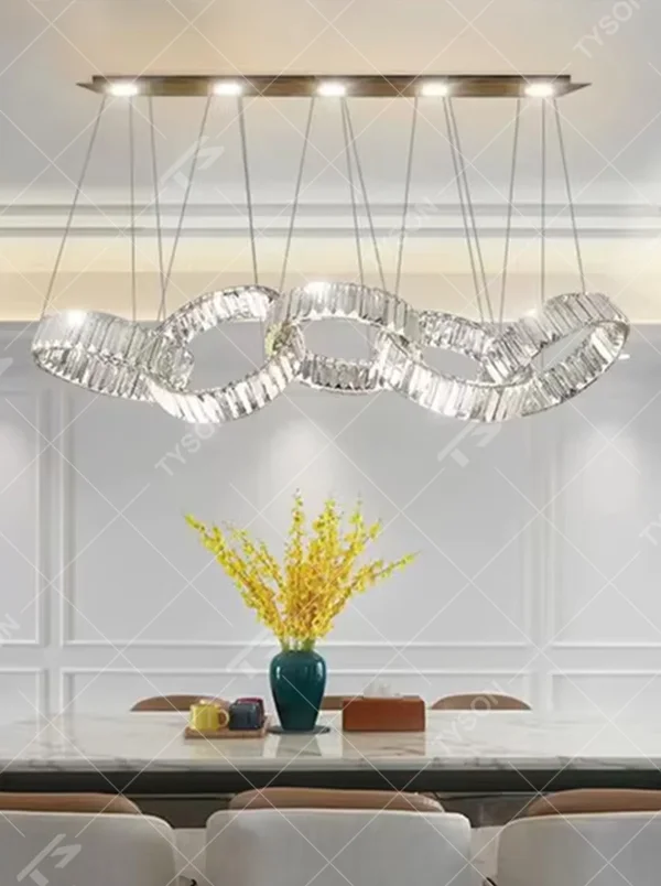 Modern light luxury chain-style ring crystal chandelier, composed of multiple transparent crystal rings connected into a flexible chain shape, paired with metal suspension rods and a long top base, combining decorative and lighting functions, suitable for dining rooms, living rooms, villas and other light luxury style spaces.