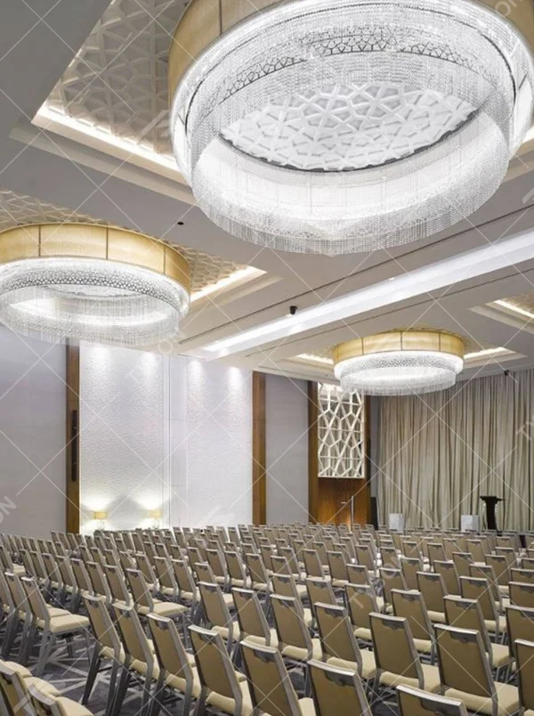 This large multi-layer round crystal ceiling lamp features a gold metal frame paired with multi-layer crystal tassels and a geometric texture lampshade, with light refracting a brilliant halo through the crystals, serving both lighting and decorative purposes, suitable for large high-end commercial spaces such as hotel banquet halls and conference centers.
