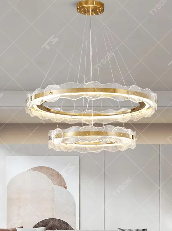 A modern light luxury style double-layer ring chandelier, featuring a gold metal frame paired with transparent glass panels with water ripple texture. It emits a soft and brilliant glow when lit, combining decorative appeal with practical illumination, ideal for creating a high-end and elegant space atmosphere.