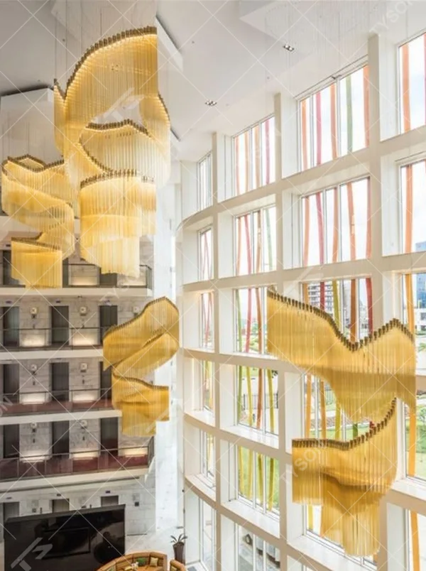 This gilded wave art chandelier is composed of layered gold acrylic strips forming a flowing wave shape, like floating golden ribbons, serving both lighting and installation art purposes, suitable for high-ceiling commercial spaces such as hotel lobbies and convention centers.