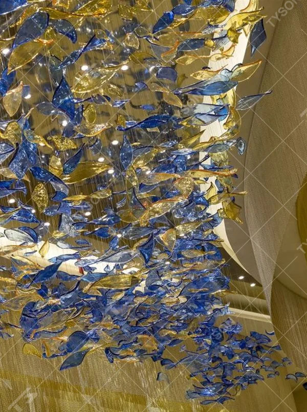 This blue-gold gradient liuli leaf art chandelier is made of liuli leaf-shaped ornaments, layered to create a flowing visual effect. Light refracts through to emit a colorful halo, serving both lighting and installation art purposes, suitable for luxury spaces such as hotel lobbies and high-end clubs.