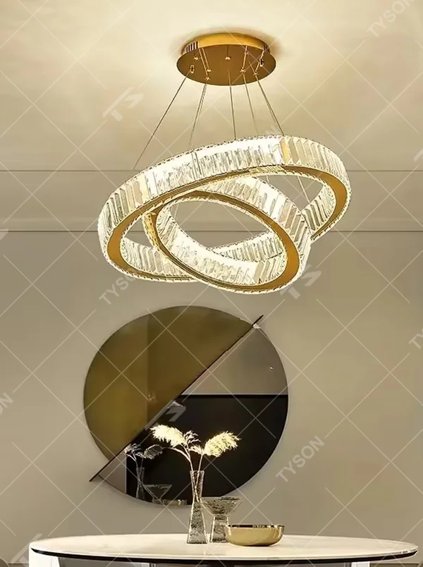 This chandelier features a core shape of multi-layer rings of varying sizes, with a lamp body made of high-transparency crystal material, paired with delicate metal suspension wires and a ceiling plate. The light presents a bright and soft gradient glow after passing through the crystal, combining modern design and luxurious texture. It is not only the core lighting tool for high-ceiling spaces, but also an artistic installation that enhances the space's style, suitable for a variety of modern light luxury style soft decoration scenarios.