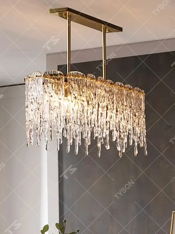 This modern light luxury linear chandelier features a gold metal frame paired with icicle-shaped transparent crystal pendants. Light refracts through the crystals to emit a brilliant and soft glow, serving both lighting and decorative purposes, suitable for modern light luxury spaces such as dining rooms and villa living rooms.