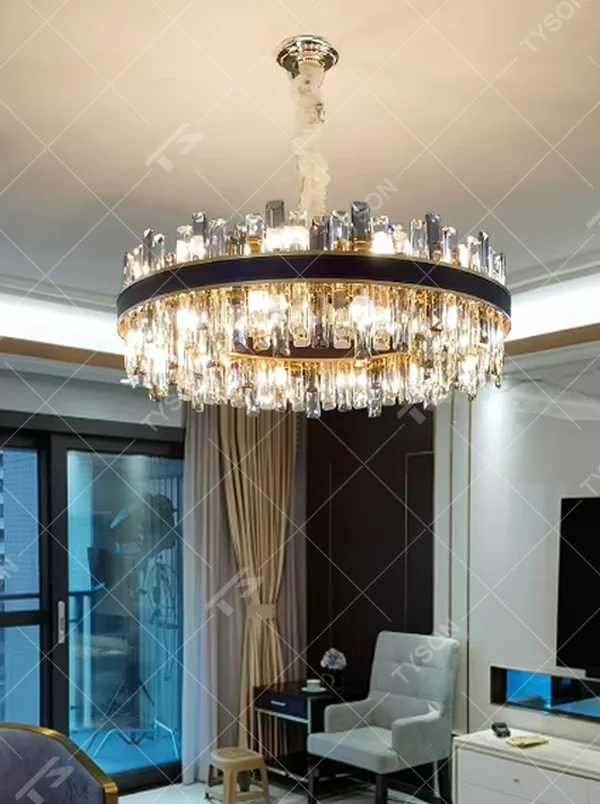 This light luxury black-gold double-layer round crystal chandelier features a black metal frame with crystal strips on the upper layer, and a gold frame with hanging faceted crystals on the lower layer. Light refracts through the crystals to emit a brilliant glow, serving both lighting and decorative purposes, suitable for modern light luxury spaces such as living rooms and dining rooms.