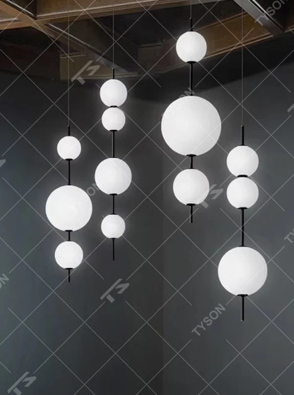 This minimalist string ball chandelier features black suspension rods connecting white spherical lampshades of varying sizes, with light refracting a soft halo through the frosted shades, serving both lighting and decorative purposes, suitable for modern minimalist commercial spaces such as restaurants and cafes.