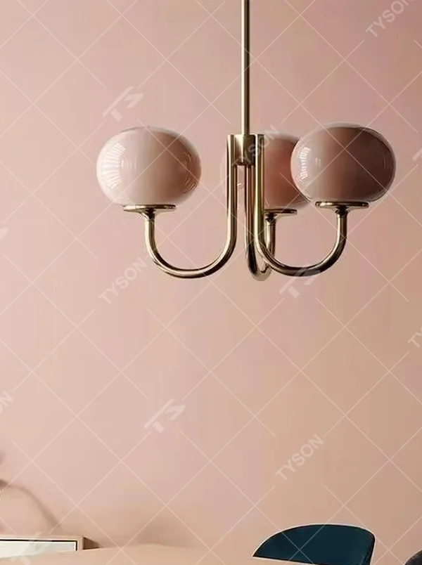 A French girly-style 3-head chandelier, featuring a gold metal curved frame paired with pink gradient glass ball lampshades (larger in the center, smaller on both sides). It emits a soft warm glow when lit, combining decorative appeal with practical illumination, ideal for creating a sweet and romantic space atmosphere.