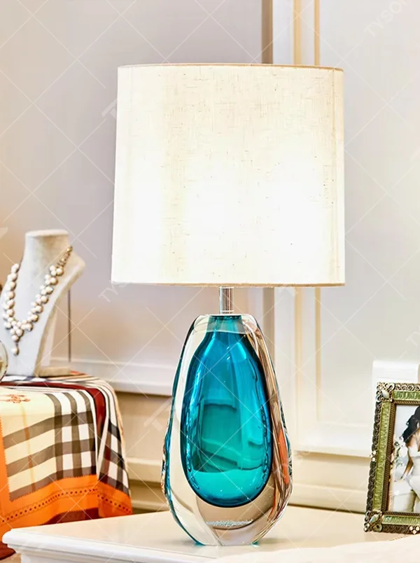 This is a fresh light luxury glass table lamp, with a royal blue fabric lampshade paired with a blue-green gradient hand-blown glass base, featuring both decorative and lighting functions, ideal for warm indoor scenarios such as bedroom nightstands and living room side tables.