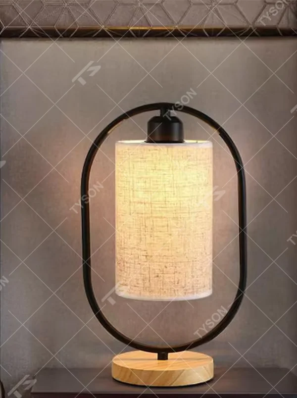 This is a modern minimalist oval frame table lamp, with a black metal oval stand paired with a beige linen lampshade and a solid wood base, featuring both decorative and lighting functions, ideal for warm indoor scenarios such as bedroom nightstands and living room side tables.