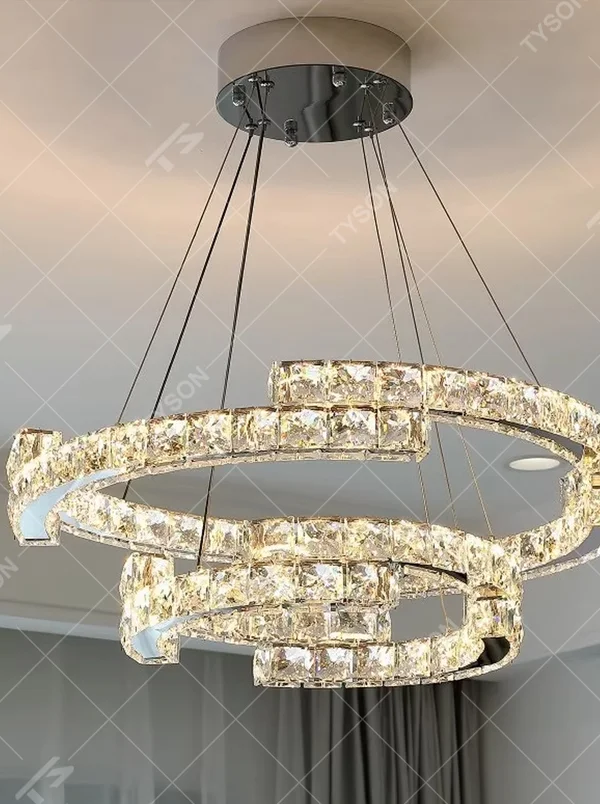 This light luxury interlaced ring crystal chandelier features a multi-layer flowing ring shape made of metal frames and crystal strips, with light refracting a brilliant halo through the crystals, serving both lighting and decorative purposes, suitable for modern light luxury spaces such as living rooms and dining rooms.