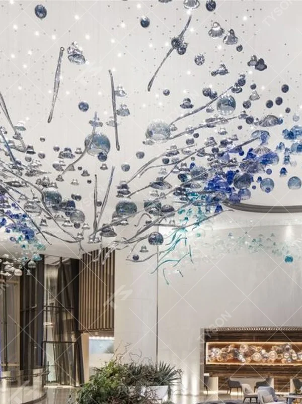 This blue-tone liuli bubble art chandelier is composed of gradient blue and transparent glass bubbles intertwined with metal lines, presenting a dynamic shape like marine plankton. Light refracts through the liuli to emit a transparent and soft halo, serving both lighting and installation art purposes, suitable for high-end commercial spaces such as hotel lobbies and art exhibition halls.