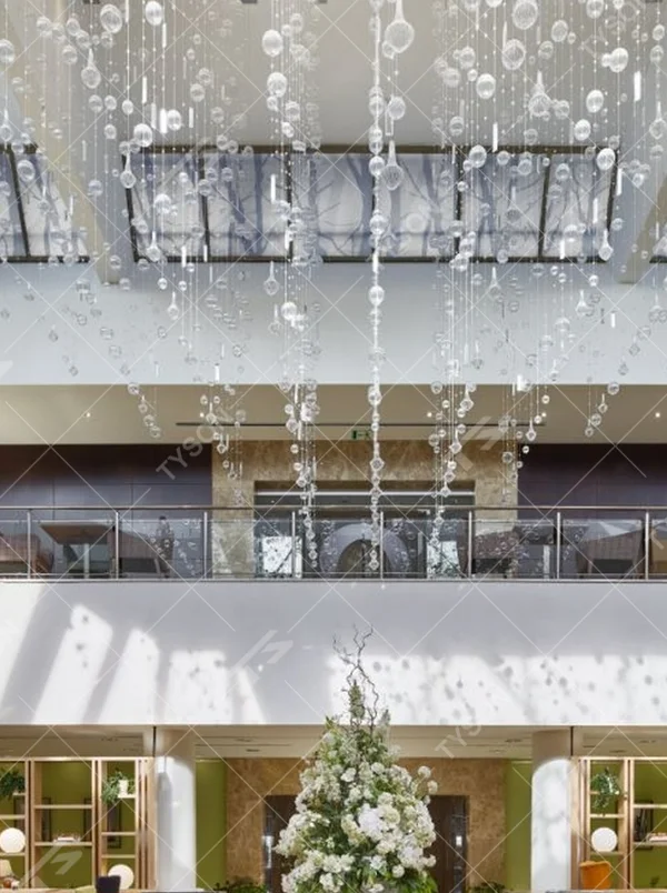 This large artistic bubble chandelier is composed of a large number of transparent glass bubble balls hung in a staggered manner by metal wires, presenting a visual effect like scattered starry sky. The light refracts through the bubbles to emit soft and transparent light spots, serving both lighting and decorative purposes, suitable for high-ceiling commercial spaces such as hotel lobbies and shopping mall atriums.