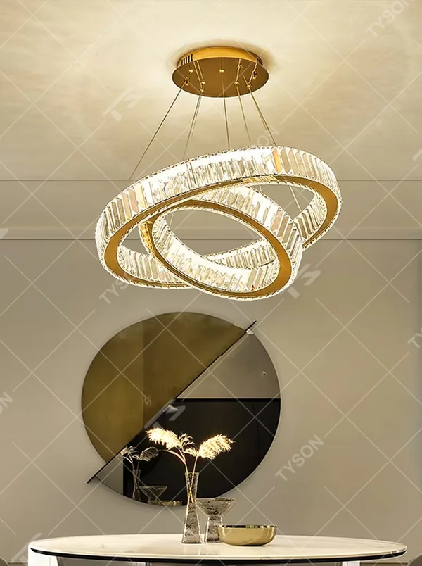 This is a light luxury three-ring interlaced crystal chandelier, with a gold metal frame inlaid with high-transparency crystal strips, presenting a dynamic ring interlaced shape, with brilliant and soft light, both decorative and lighting functions, ideal for high-end indoor spaces such as dining rooms and living rooms.