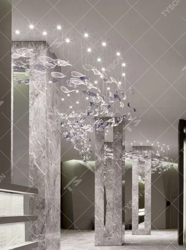 This modern artistic bird-shaped chandelier consists of transparent and gradient blue-purple leaf-shaped glass ornaments hung staggered, arranged in an arc streamline, with point light sources to create a dynamic visual effect, serving both lighting and decorative purposes, suitable for high-end commercial spaces such as luxury sales offices and hotel lobbies.
