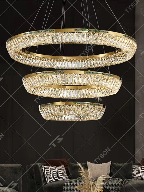 This modern light luxury multi-layered ring crystal chandelier features a gold metal frame, with each ring inlaid with transparent long crystals arranged in concentric circles. When lit, light refracts through the crystal to emit a brilliant and luxurious glow, combining layered design with an ambient atmosphere. Ideal for high-ceiling living rooms, villa foyers, hotel lobbies, and other spaces, it adds an elegant and exquisite touch to modern light luxury or European-style luxury environments.