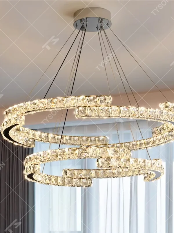 This modern light luxury double-ring interwoven crystal chandelier features a silver metal base, inlaid with transparent crystals to create a dynamic double-ring interwoven shape. When lit, light refracts through the crystal to emit a brilliant and dynamic glow, combining a futuristic feel with an ambient atmosphere. Ideal for living rooms, dining rooms, light luxury apartments, and other spaces, it adds an exquisite and sophisticated touch to modern minimalist or light luxury home environments.
