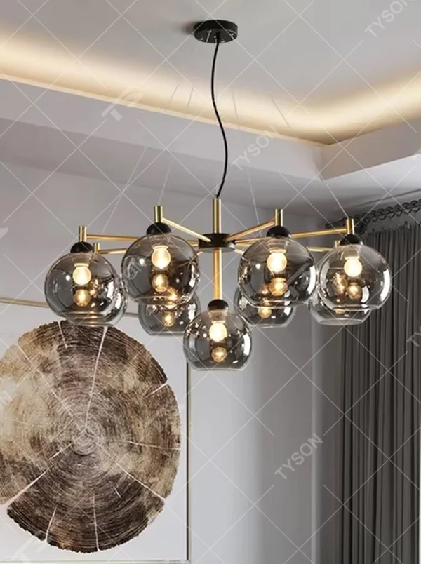Modern light luxury black and gold branch chandelier, featuring a radial frame in black and gold metal paired with gradient smoky gray glass ball lampshades. Its sophisticated and layered design combines style and ambiance, making it a high-end decorative lighting fixture that elevates the space's aesthetic.