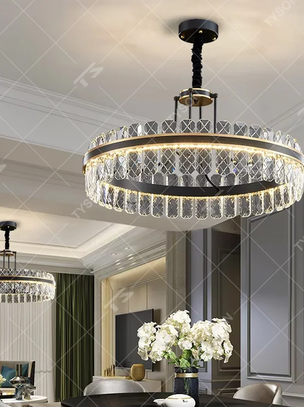 This modern light luxury two-layer circular crystal chandelier features a black metal frame, inlaid with transparent crystal strips with diamond textures to form a double-layered circular shape, paired with a height-adjustable black suspension rod. When lit, light refracts through the crystal to emit a brilliant and luxurious glow, combining a bold texture with an ambient atmosphere. Ideal for living rooms, dining rooms, light luxury apartments, and other spaces, it adds an exquisite and sophisticated touch to modern minimalist or industrial-style home environments.