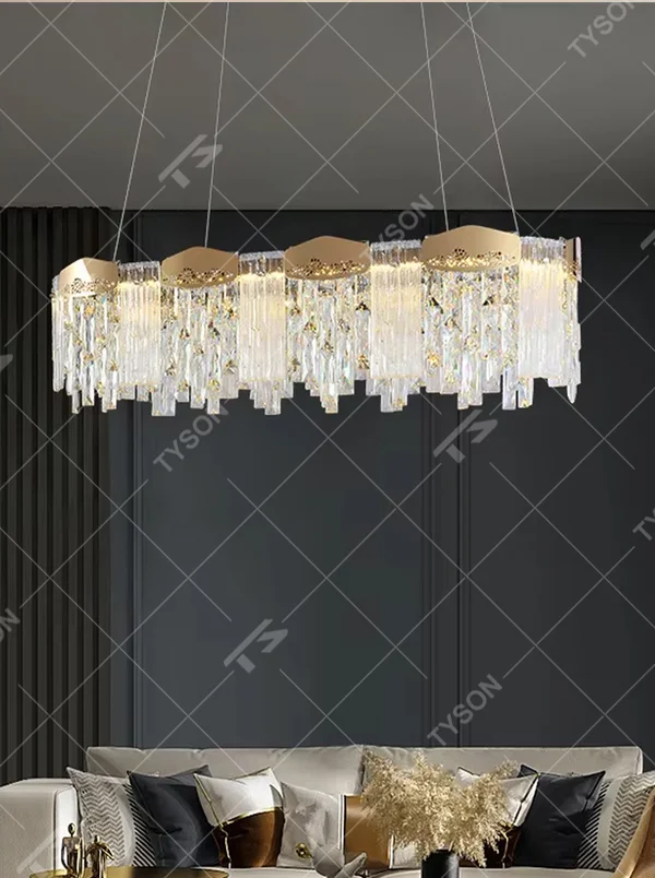 This modern light luxury linear crystal chandelier features a gold metal frame, with dense transparent long crystals hanging down and hollow-textured metal decorative blocks on top. When lit, light refracts through the crystal to emit a brilliant and soft glow, combining an exquisite texture with an ambient atmosphere. Ideal for dining rooms, bars, light luxury apartments, and other spaces, it adds an exquisite and sophisticated touch to modern minimalist or light luxury home environments.